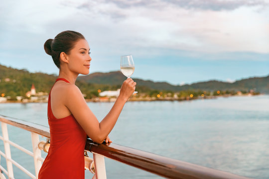 Luxury cruise ship travel elegant Asian woman drinking wine glass drink enjoying watching sunset from boat deck over ocean in summer vacation destination. Cruising sailing away on holiday.
