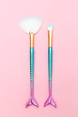Makeup brush in the shape of a mermaid on a pink background. Vertical