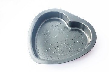 Heart shape baking dish. Metal heart shaped baking dish isolated on white background. Oil droplets