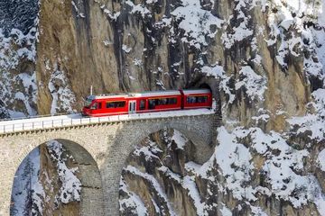 Foto op Plexiglas Landwasserviaduct A red train is coming out of the tunnel of the famous Landwasser Viaduct, which ia a wonder of Swiss mountain railway engineering in 1901 and a unesco heritage since 2008.