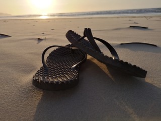 Beautiful sunset with sandal on the beach, walking barefoot on the beach.