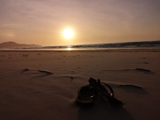 Beautiful sunset with sandal on the beach, walking barefoot on the beach.