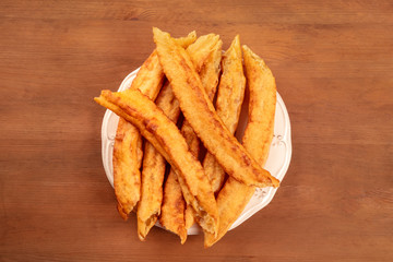 An overhead photo of traditional Spanish porras, a typical Madrid Sunday breakfast, on a dark rustic wooden background with copy space