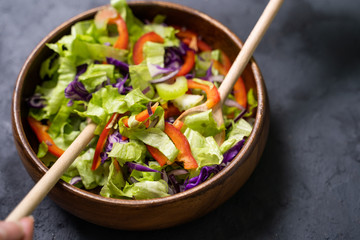 Mix salad leaves in a black bowl over dark slate, stone or concrete background.