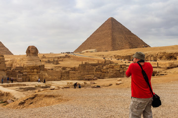 Fototapeta na wymiar Young man taking a photos of the pyramids of Giza in Cairo Egypt