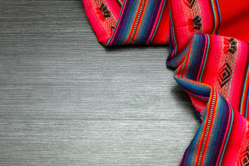 Bright multicolor tablecloth on wooden table. Fabric texture. Copy space 