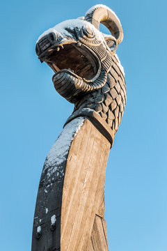 wooden dragon head on Drakkar on blue sky background. Focus on head and eyes