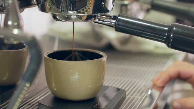 Brewing espresso coffee into a cup in a commercial espresso maker in Medellin, Colombia