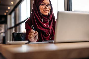 Muslim woman having video chat at cafe - Powered by Adobe