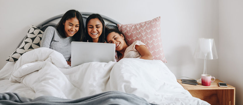 Girls Watching A Movie On Laptop Lying On Bed