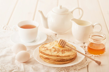 Healthy summer breakfast, homemade classic american pancakes with honey,cozy morning, copy space. Pancakes, teapot, honey on white wooden table. Pancake week. russian traditional holiday Maslenitsa