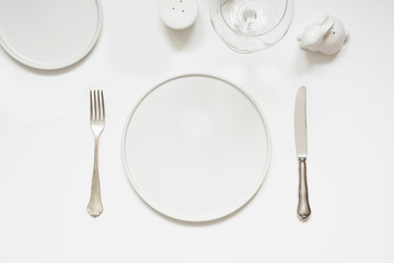 Festive modern white table setting. Plates and cutlery on white. View from above.