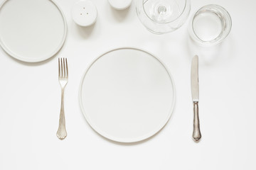 Festive modern white table setting. Plates and cutlery on white. View from above.