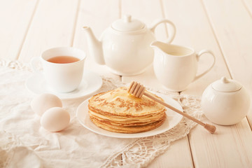 Healthy summer breakfast, homemade classic american pancakes with honey,cozy morning, copy space. Pancakes, teapot, honey on white wooden table. Pancake week. russian traditional holiday Maslenitsa
