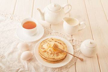 Obraz na płótnie Canvas Healthy summer breakfast, homemade classic american pancakes with honey,cozy morning, copy space. Pancakes, teapot, honey on white wooden table. Pancake week. russian traditional holiday Maslenitsa