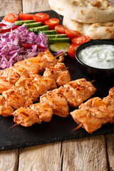 Traditional Taouk chicken kebab with fresh salad, yogurt sauce and pita bread close-up. vertical
