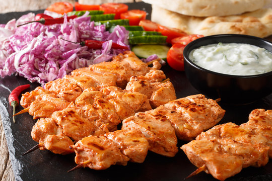 Close-up of chicken skewers with fresh salad, yogurt sauce and pita bread on a slate. horizontal