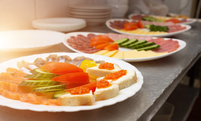Sliced on a plate in the form of sausage ham and vegetables, sandwiches with red caviar, restaurant