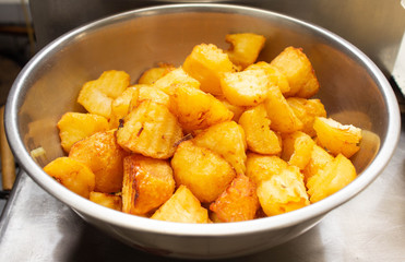 Fried potatoes with a golden crust in a deep fryer, rustic slices, lobule