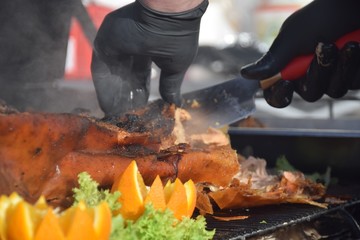 Ganzes, gegrilltes Schwein auf einem Grill im Rauch mit Salat und Orangen wird mit einem scharfen...