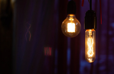 Two filament lamps hang in a cafe, copy space, night
