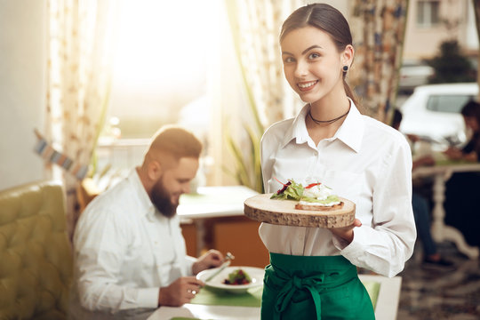 Portrait young waitress holding sandwich on plate