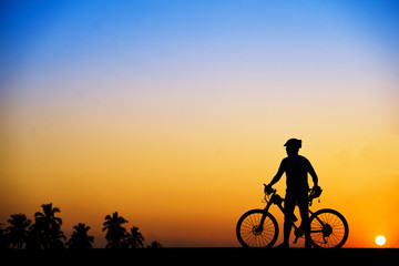 Silhouette of cyclist with mountain bike on beautiful sunset time at the beach