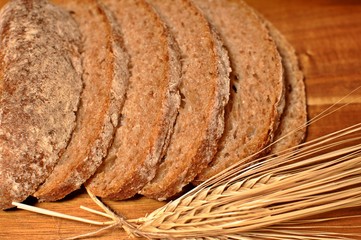 Top table of slices of brown cereal healthy bread with dried wheat decoration on wooden table background
