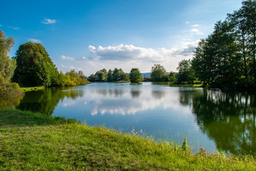 Beautiful fish pond near Diviaky, Turcianske Teplice, Slovakia. Sky and trees mirror reflection in...