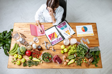 Dietitian writing diet plan, view from above on the table with different healthy products and...
