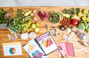 Dietitian writing diet plan, view from above on the table with different healthy products and...