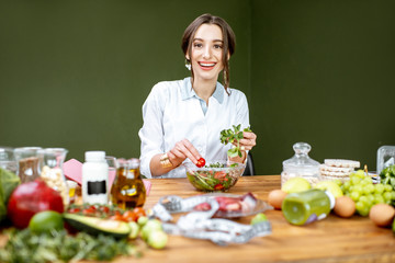 Woman dietitian working on a healthy diet making a salad with different raw products at the working...