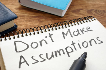 Don't Make Assumptions. Notepad with marker on a table.