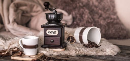 home still life in the interior with an old coffee grinder and a Cup of coffee beans, on the background of a cozy home decor