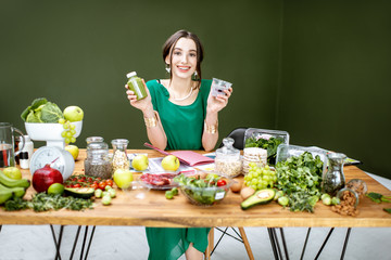 Portrait of a beautiful woman as a dietitian sitting with smoothie, chia pudding and various...