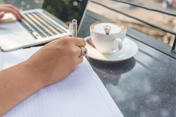 Businessman typing by left hand, writing note by right hand