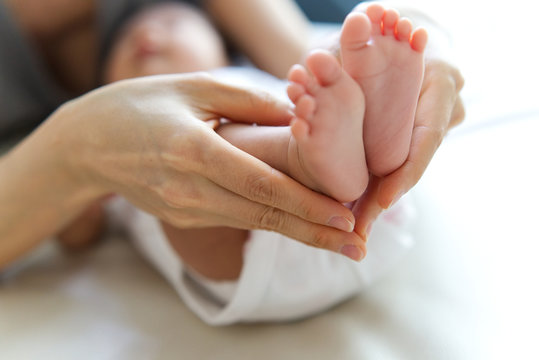 Baby girl feet in her mother hand. Tiny Newborn Baby's feet on female heart Shaped hands seen in close up view. Beautiful conceptual image of Maternity. Mom and baby, happy Family concept.