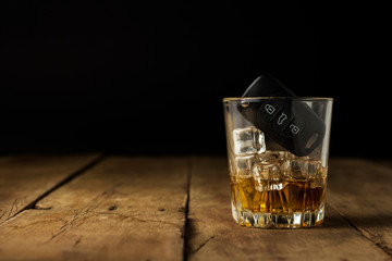 Car keys in a glass with an alcoholic drink on a wooden background. Drunk driving concept, stop drinking and driving.