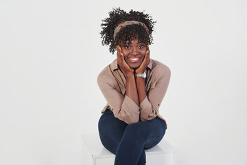 Cheerful girl smiling while sits on the chair in studio with white background