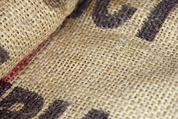Close up picture of folded empty old burlap with big printed unrecognisible letters. Ecological, natural fabric packing issue, rustic background. Copy space.