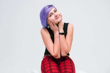 Talk to me - Concept portrait of a beautiful girl with purple hair on a white background sitting on a cube and talking.