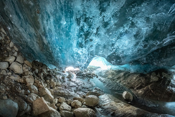 an ice cave in a mountain glacier, a column of the purest ice hangs above the stones of the Alibek...