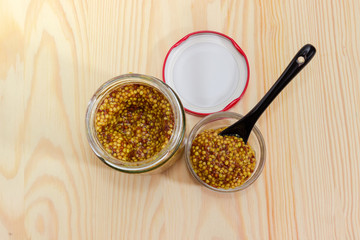 French mustard in glass jar and small bowl with spoon