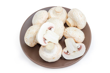 Uncooked cultivated button mushrooms on a brown dish