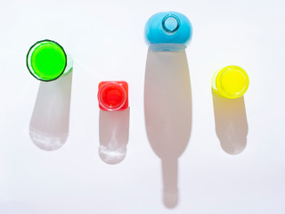 Glass containers with different colors of paint and shadow from them