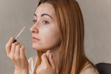 Fototapeta premium Woman applying foundation and concealer makeup. Do it yourself makeup for problem skin 