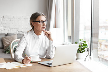 Candid shot of gorgeous serious senior sixty year old female personal coach wearing spectacles...