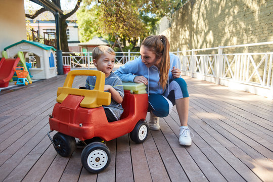 Kinderg&auml;rtnerin und ein Junge im Tretauto