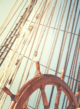 Skipper's wheel and sea tackles on the mast on a tall ship. Rigging ropes at blur background on a sailing vessel for your concept in marine style.