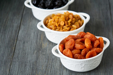 Various dried fruits in white bowls on wooden background